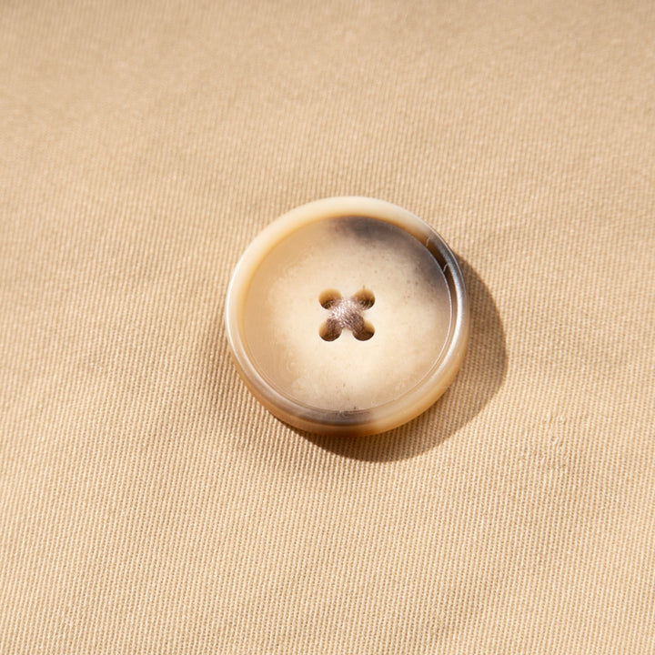 A trench coat, with a pink tutu sewn at the back. Two pockets are at the front and a buttoned panel on the upper left corner. Fastened from the front with faded dark/light brown coat buttons. 