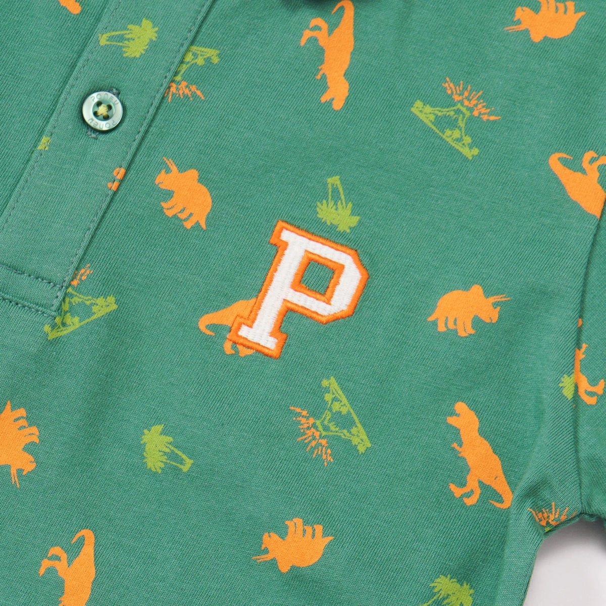 Green Cotton Polo, Orange T-Rex, Triceratops and Volcano Prints. Rib-Knit Collar, Emroidered Poney Logo, Front buttoned and Longer Hem.