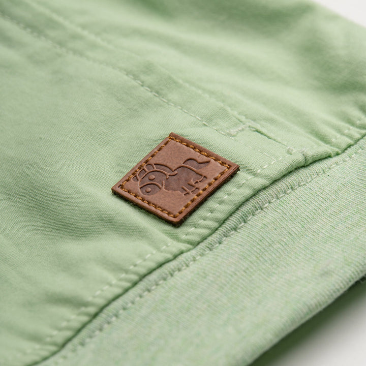 Light green, short sleeve top, button strapped shoulder and a cute logo tag attached. 