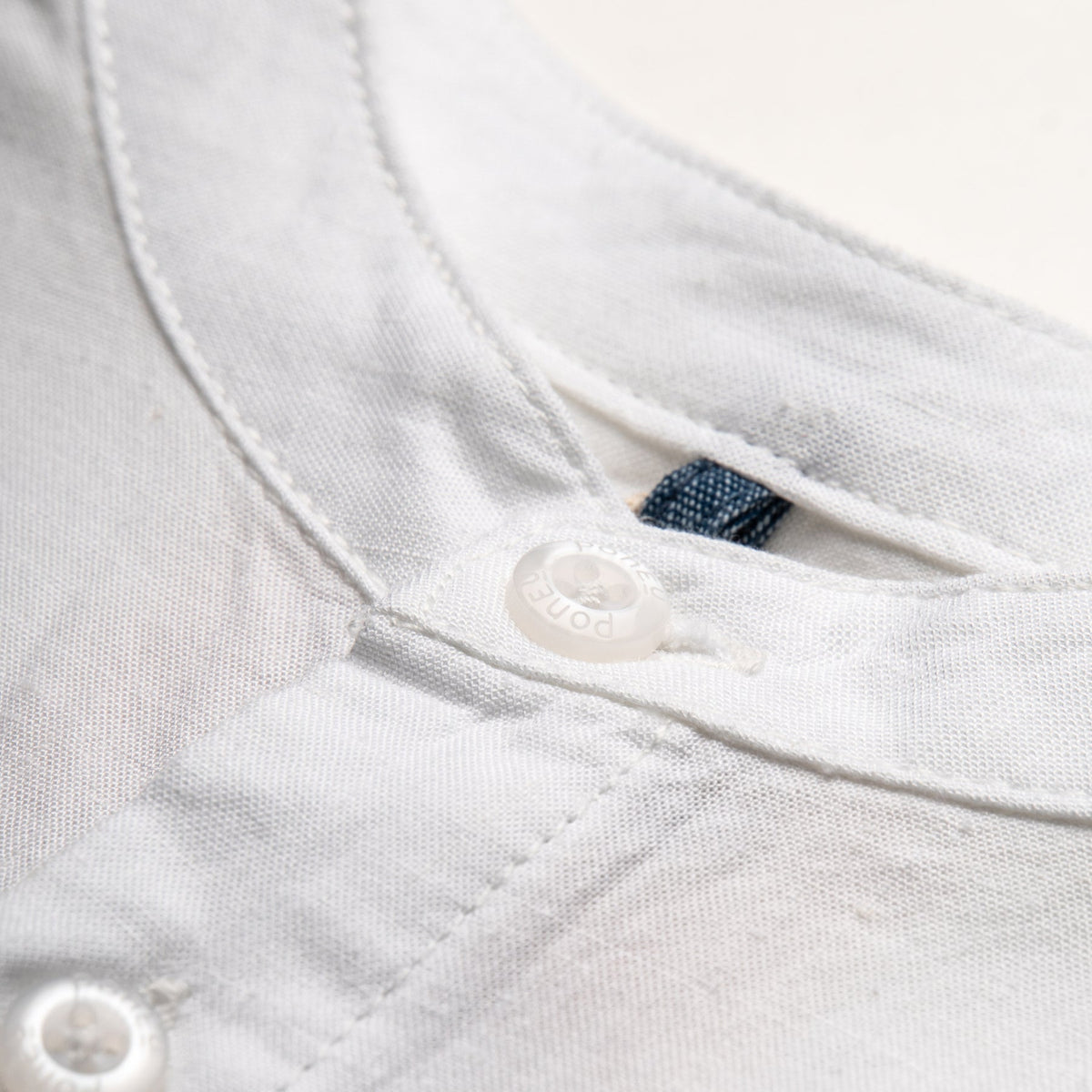 White fish tank shirt, short sleeve, front fastening. Back hem slightly longer than the front. 