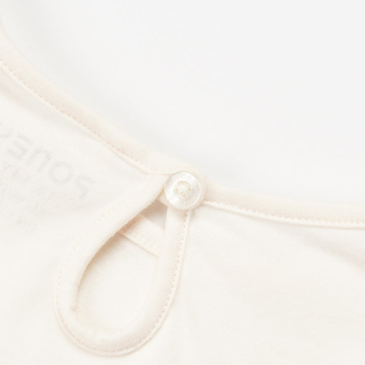 Creme Long sleeve t-shirt with a chunky dino print, elasticated cuffs and a buttoned nape.