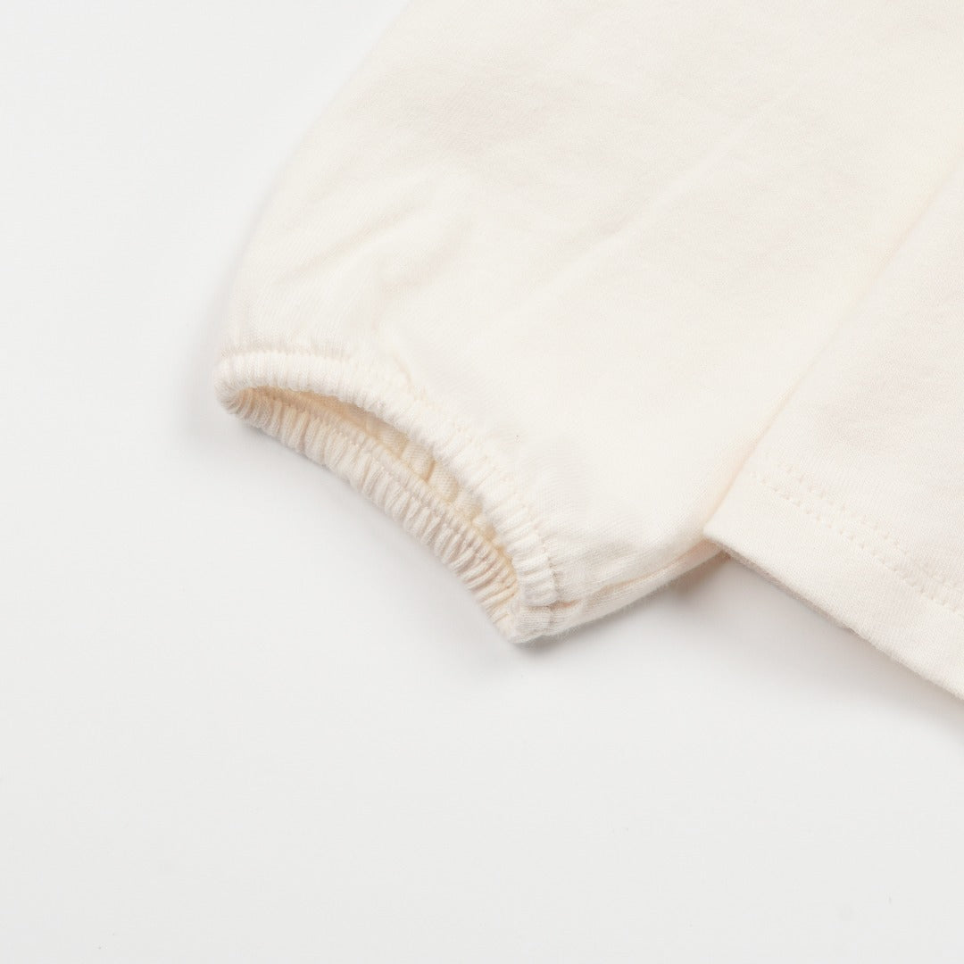 Creme Long sleeve t-shirt with a chunky dino print, elasticated cuffs and a buttoned nape.