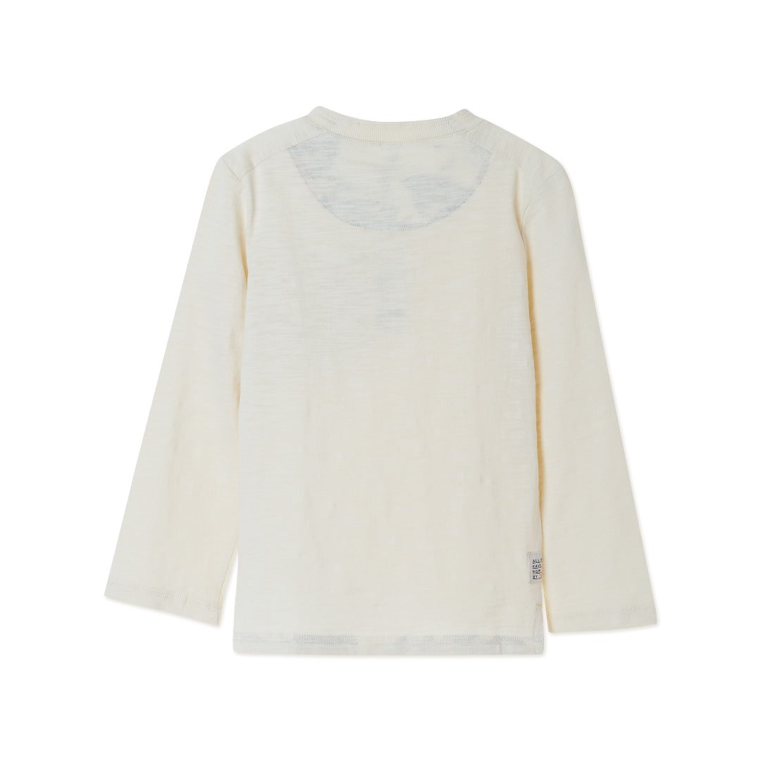 Cream colored, long sleeve top, hidden floral strap visible at the nape, front pocket and backside hem. 